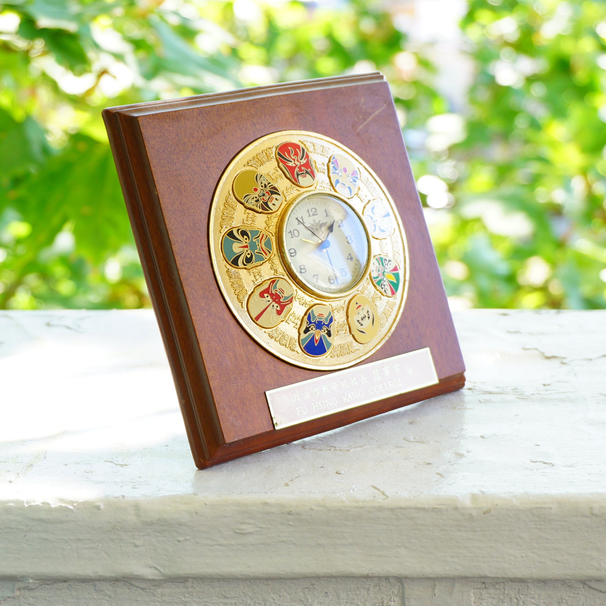 Vintage Fu Hsing Kang College Gold Tone 9 Mask Clock with a Wooden Frame.