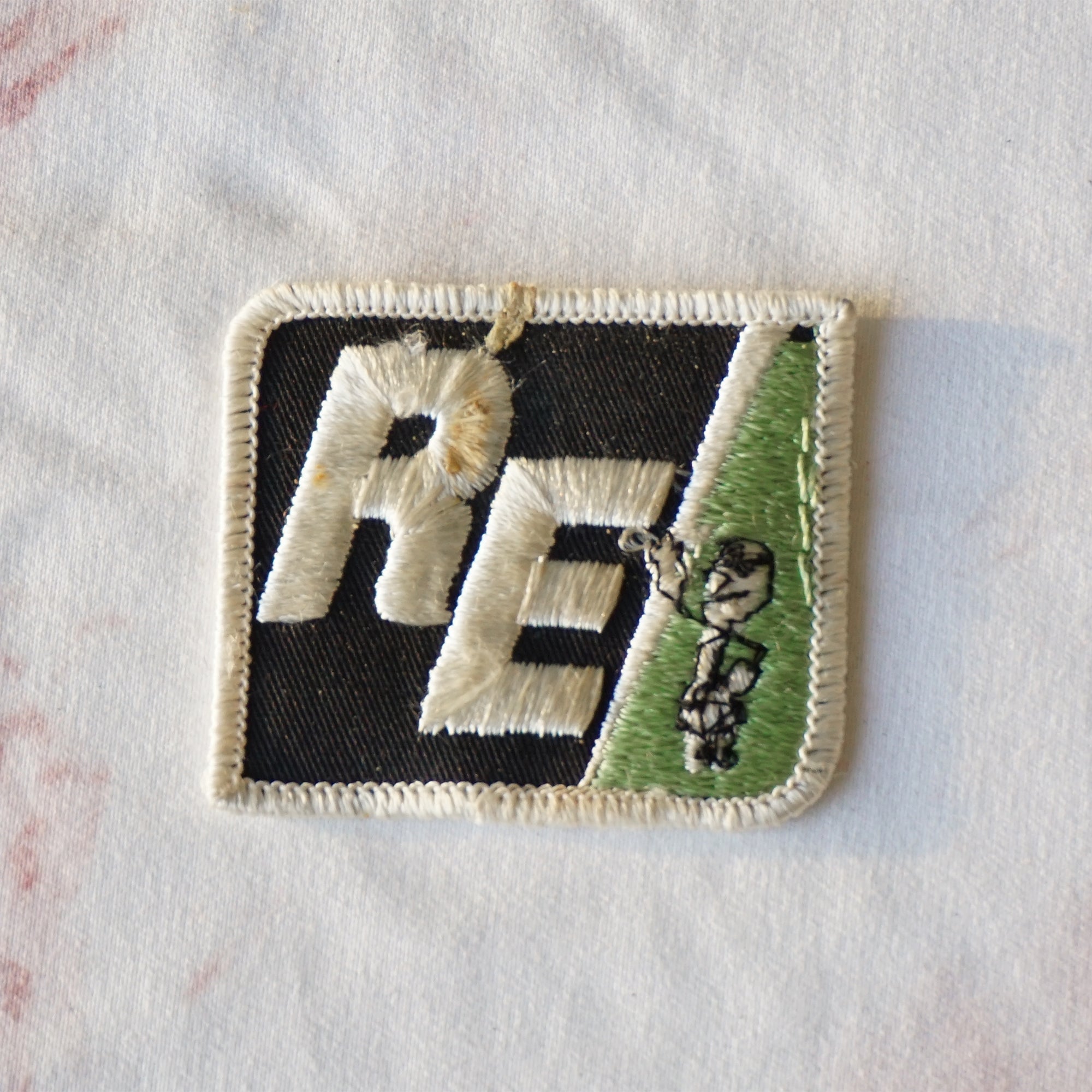 1980s Vintage 2.25" RE Rural Electric Clothing Patch with Lightning and Person. Black, White and Green Colors.